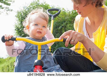 Mother with daughter on tricycle View Large Photo Image Stock Photo - Mother with daughter on tricycle. Fotosearch