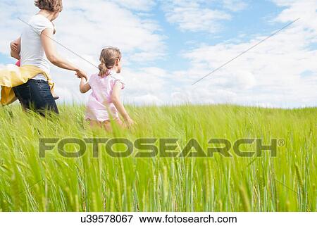Stock Photo - Mother with two daughters in field. Fotosearch