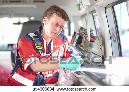 Paramedic in ambulance checking equipment list View Large Photo Image Picture - Paramedic in ambulance checking equipment list. Fotosearch