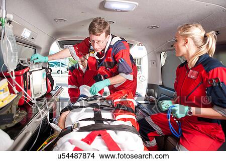 Picture - Paramedics checking patient in ambulance. Fotosearch