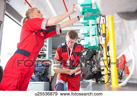Stock Photo - Paramedics in ambulance listing equipment. Fotosearch
