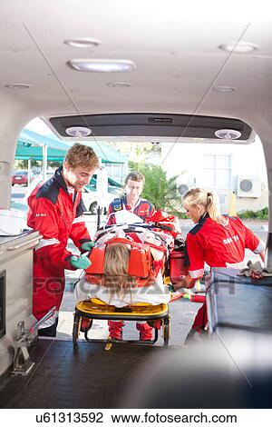 Stock Image - Paramedics lifting patient into ambulance. Fotosearch