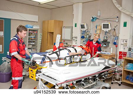 Stock Photo - Paramedics moving patient to hospital bed. Fotosearch