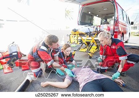 Stock Photo - Paramedics tending patient lying on road. Fotosearch