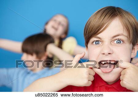 Portrait of boy sticking out tongue, blue background View Large Photo Image Stock Photography - Portrait of boy sticking out tongue, blue background. Fotosearch