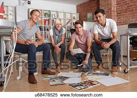 Stock Photography - Portrait of colleagues with papers on floor. Fotosearch