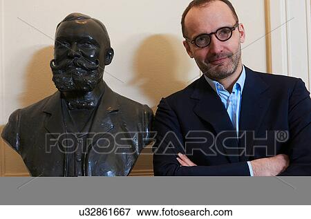 Stock Photo - Portrait of confident professional man next to statue. Fotosearch