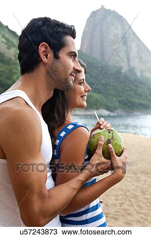 Stock Image - Portrait of couple on beach with Sugarloaf Mountain, Rio de Janeiro, Brazil. Fotosearch