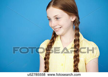 Stock Photo - Portrait of girl with plaits wearing yellow school dress. Fotosearch