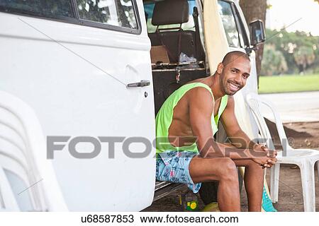 Stock Image - Portrait of man sitting in campervan doorway. Fotosearch