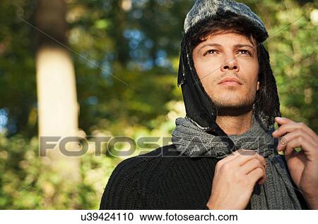 Stock Image - Portrait of man wearing hat and scarf, looking away. Fotosearch