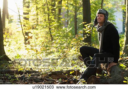 Portrait of mid adult man sitting on log in forest View Large Photo Image Stock Image - Portrait of mid adult man sitting on log in forest. Fotosearch