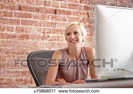 Portrait of mid adult woman at desk with brick wall View Large Photo Image Stock Image - Portrait of mid adult woman at desk with brick wall. Fotosearch