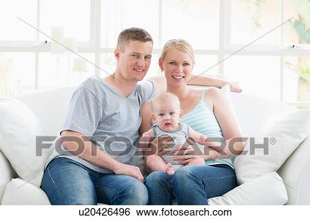 Portrait of parents and baby sitting on sofa View Large Photo Image Stock Photograph - Portrait of parents and baby sitting on sofa. Fotosearch