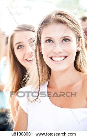 Stock Image - Portrait of young blonde woman with plait, looking up smiling. Fotosearch