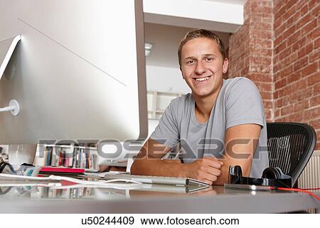 Portrait of young man at desk View Large Photo Image Stock Photo - Portrait of young man at desk. Fotosearch