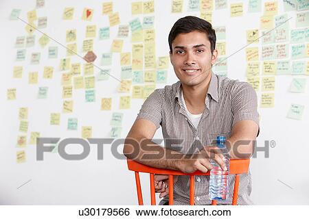 Stock Photograph - Portrait of young man with adhesive notes in background. Fotosearch