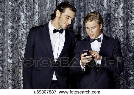 Portrait of young men looking at mobile phone View Large Photo Image Stock Photo - Portrait of young men looking at mobile phone. Fotosearch