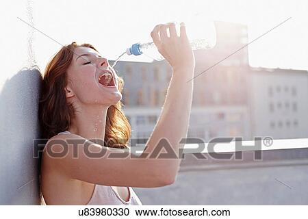 Portrait of young woman drinking mineral water View Large Photo Image Stock Image - Portrait of young woman drinking mineral water. Fotosearch