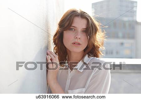 Stock Photograph - Portrait of young woman leaning against wall. Fotosearch