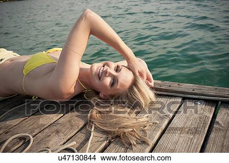 Portrait of young woman lying on lake pier View Large Photo Image Picture - Portrait of young woman lying on lake pier. Fotosearch