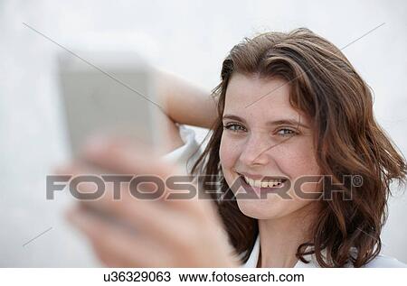Portrait of young woman photographing self with camera phone View Large Photo Image Stock Image - Portrait of young woman photographing self with camera phone. Fotosearch