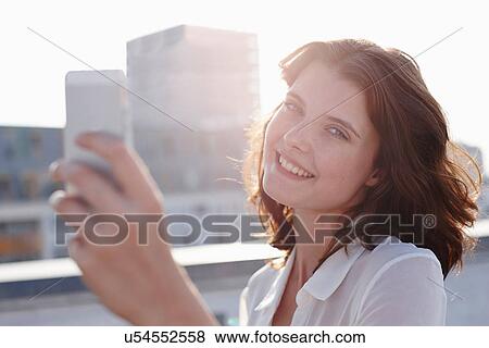 Portrait of young woman photographing self with camera phone View Large Photo Image Stock Photo - Portrait of young woman photographing self with camera phone. Fotosearch