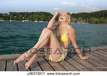 Stock Photo - Portrait of young woman posing on lake pier. Fotosearch