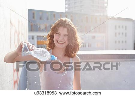 Portrait of young woman pouring mineral water View Large Photo Image Stock Image - Portrait of young woman pouring mineral water. Fotosearch