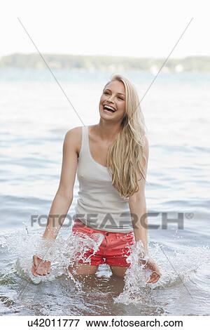 Stock Photo - Portrait of young woman splashing in lake. Fotosearch