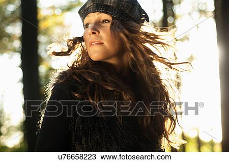 Stock Image - Portrait of young woman wearing hat spinning around. Fotosearch