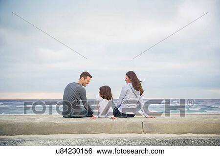 Rear view of family sitting on beach View Large Photo Image Stock Photograph - Rear view of family sitting on beach. Fotosearch