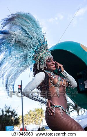 Stock Image - Samba dancer using pay phone, Ipanema Beach, Rio De Janeiro, Brazil. Fotosearch