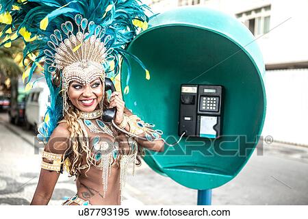 Stock Photography - Samba dancer using pay phone, Ipanema Beach, Rio De Janeiro, Brazil. Fotosearch