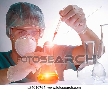 Picture - Scientist pouring liquid from pipette. Fotosearch