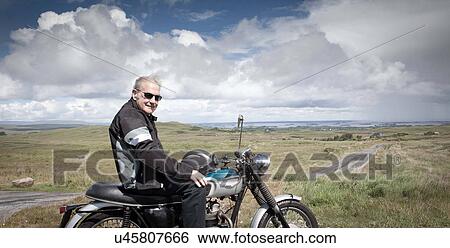 Stock Photograph - Senior male motorcyclist taking a break. Fotosearch