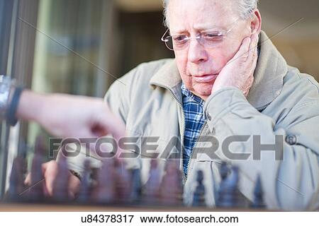 Stock Photo - Senior male playing chess with son. Fotosearch