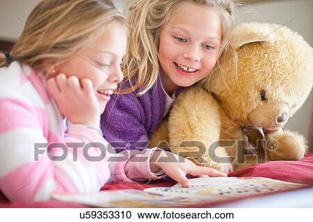 Stock Image - Sisters and teddy bear reading storybook. Fotosearch