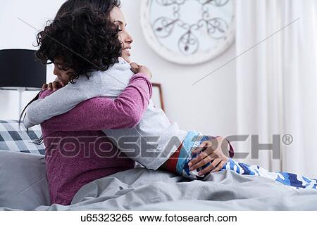 Stock Photography - Son hugging mother in bed. Fotosearch