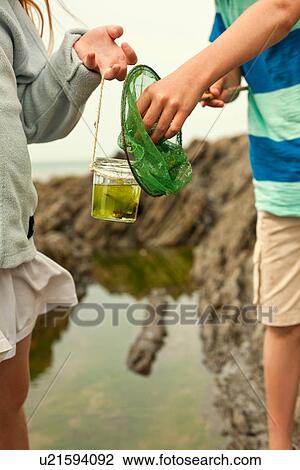 Teenage boy and girl holding fishing net and jar, close up View Large Photo Image Stock Image - Teenage boy and girl holding fishing net and jar, close up. Fotosearch