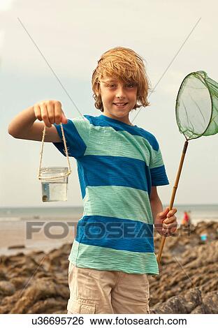Stock Photograph - Teenage boy holding jar and fishing net. Fotosearch