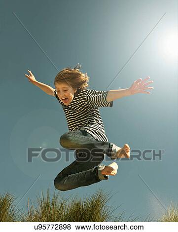 Teenage boy jumping against clear blue sky View Large Photo Image Stock Photo - Teenage boy jumping against clear blue sky. Fotosearch
