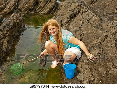 Picture - Teenage girl rock pooling. Fotosearch