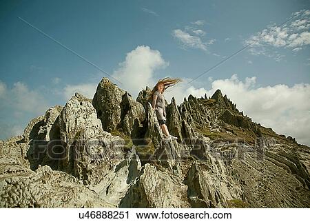Stock Image - Teenage girl standing on rocks. Fotosearch