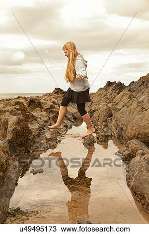 Teenage girl walking over rock pool View Large Photo Image Stock Image - Teenage girl walking over rock pool. Fotosearch