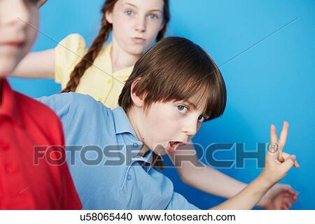 Three children against blue background, boy making peace sign View Large Photo Image Stock Image - Three children against blue background, boy making peace sign. Fotosearch