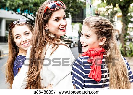Stock Photo - Three female friends looking over shoulders. Fotosearch