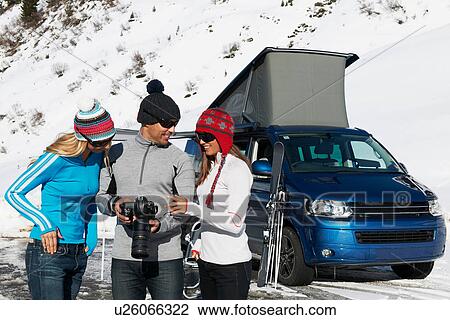 Stock Image - Three friends with camera, Obergurgl, Austria. Fotosearch