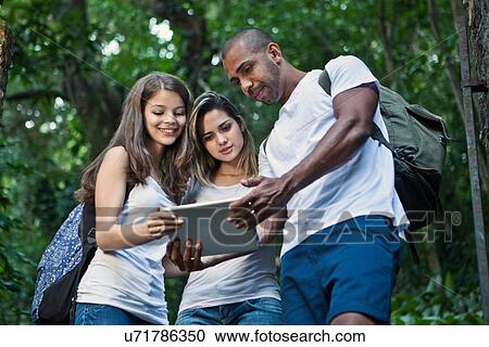 Three young friends in jungle with digital tablet View Large Photo Image Stock Image - Three young friends in jungle with digital tablet. Fotosearch