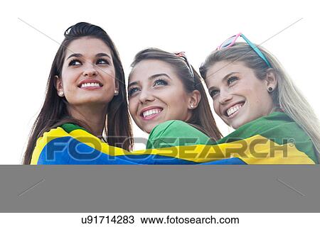 Stock Image - Three young women wrapped in Brazilian flag. Fotosearch